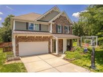 Charming two-story home featuring stone and siding, a two-car garage, and manicured landscaping at 516 Fair Oaks Dr, Fort Mill, SC 29708