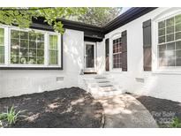 Charming home features a white brick facade, black trim, and lush landscaping for appealing curb appeal at 6128 Coatbridge Ln, Charlotte, NC 28212