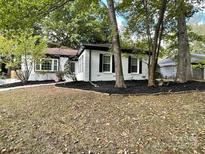 Charming single-story home featuring manicured landscaping and a classic design with black shutters and fresh mulch at 6128 Coatbridge Ln, Charlotte, NC 28212