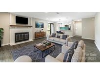 Comfortable living room with a fireplace, gray rug, and views into kitchen at 712 Mallard Head Ln, Mooresville, NC 28117