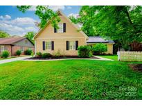 Charming two-story home with yellow siding, black shutters, and a well-manicured green lawn at 7521 Surreywood Pl, Charlotte, NC 28270