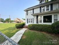 Charming two-story home with white siding, black shutters, and manicured landscaping in the front yard at 156 Spruce St, Badin, NC 28009