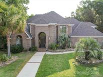 Charming brick home featuring a landscaped front yard with mature palm trees and a brick and stone facade at 15708 Eagleview Dr, Charlotte, NC 28278