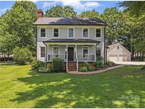 Charming two-story home features a welcoming front porch, complemented by a well-manicured lawn and lush landscaping at 18733 Bluff Point Rd, Cornelius, NC 28031
