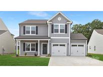 Charming two-story home featuring a two-car garage, gray siding, black shutters, and a welcoming front porch at 219 Redondo Dr # 65, Wingate, NC 28174