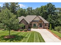 Beautiful brick home featuring a well-manicured lawn, mature trees, and a long driveway at 2341 Shiny Leaf Dr, Denver, NC 28037