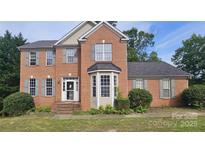 Charming two-story brick home with a bay window, gray shutters, and a well-maintained front yard at 4227 Kiser Woods Sw Dr, Concord, NC 28025