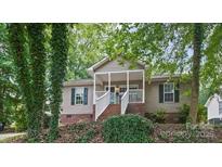 Charming home with a brick foundation, inviting front porch, and lush trees at 471 Hillandale Ne St, Concord, NC 28025