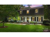 Charming two-story home featuring a lush green lawn, mature trees, and classic black shutters at 7213 Lancer Dr, Charlotte, NC 28226