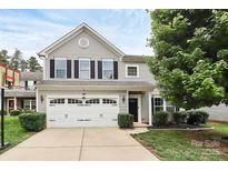 Charming two-story home featuring a two-car garage, complemented by a well-maintained front lawn and mature tree at 7434 Dover Mill Sw Ln, Concord, NC 28025