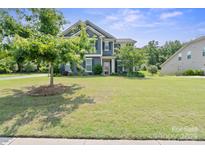 Charming two-story home boasts lush green lawn and mature trees in a well-maintained front yard at 8340 Breton Way, Harrisburg, NC 28075