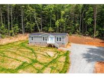 Charming home featuring a gravel driveway and lush green backdrop of tall trees at 122 River Ridge Ln, Hickory, NC 28601