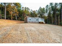 Charming home with gray siding and a welcoming white porch, nestled on a grassy hillside surrounded by trees at 122 River Ridge Ln, Hickory, NC 28601