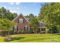 Beautiful two-story brick home with a manicured lawn and mature trees on a sunny day at 1336 Dobson Dr, Waxhaw, NC 28173