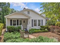 Charming home showcasing a landscaped front yard with a bench, white siding, and blue shutters at 1600 Onslow Dr, Charlotte, NC 28205