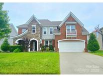 Beautiful brick and stone home featuring a well-manicured lawn and attached two car garage at 2634 Treeline Dr, Concord, NC 28027