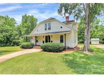 Charming white farmhouse with inviting front porch, beautiful landscaping, and a lush green lawn at 604 Ferguson Ridge Rd, Gastonia, NC 28052