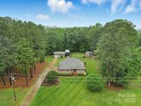 Inviting brick home featuring a well-manicured lawn, mature trees, and a detached garage at 733 Killian Rd, Stanley, NC 28164