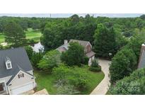 Aerial view of a brick home with a lush yard and access to a pond and golf course at 7704 Ninth Fairway Ln, Mint Hill, NC 28227