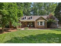 Charming brick home with a manicured lawn, covered porch, and mature trees at 10311 Windtree Ln, Charlotte, NC 28215