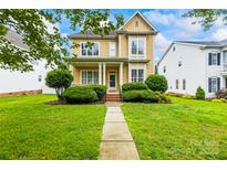 Inviting yellow two-story home with a manicured lawn and charming front porch at 187 Water Oak Dr, Mooresville, NC 28117