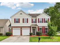 Charming two-story home featuring a brick and vinyl facade, red shutters, a well-manicured lawn and a two car garage at 5002 Abode Lily Ln, Charlotte, NC 28227