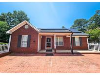 Charming brick home featuring a brick driveway, well-manicured lawn, and welcoming front porch at 501 N Johnson St, Monroe, NC 28112