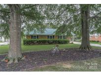 Charming brick home featuring a well-manicured lawn, mature trees, and a vintage bicycle at 6206 Clearwater Dr, Indian Trail, NC 28079