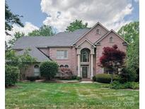 Elegant two-story brick home featuring a beautifully landscaped lawn and a grand entrance with classic architectural details at 6311 Seton House Ln, Charlotte, NC 28277