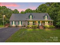 Charming ranch-style home featuring a welcoming front porch, lush lawn, and beautiful landscaping at 8632 Island Point Rd, Sherrills Ford, NC 28673