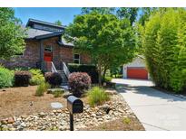 Brick home with a red door, lush landscaping, and an inviting walkway creating a warm welcome at 16525 Tulloch Rd, Charlotte, NC 28278