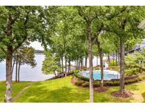 Lakefront community pool and green lawn with mature trees, offering a tranquil lakeside retreat at 303 Northwest Dr, Davidson, NC 28036