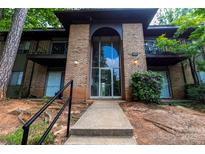 Brick apartment building featuring balconies, secure entrance, and concrete walkway at 326 Orchard Trace Ln # 3, Charlotte, NC 28213