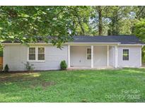 Charming single-story home with a brick facade and a cozy front porch, surrounded by lush greenery and a well-maintained lawn at 4410 Burgin St, Kannapolis, NC 28081