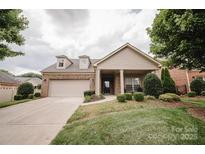 Charming brick home features a two-car garage, dormer windows, manicured landscaping, and covered front porch at 4518 Courtyard Blvd # 4, Harrisburg, NC 28075