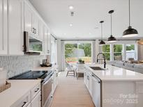 Bright modern kitchen with white cabinets, stainless appliances, and breakfast nook with backyard views at 502 Webster Ln, Cramerton, NC 28032