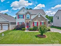 Charming two-story home featuring a well-manicured lawn, brick accents and red shutters at 511 Rough Hewn Ln, Rock Hill, SC 29730