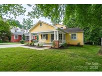 Charming yellow home boasts a welcoming front porch, lush lawn, and inviting curb appeal at 660 Ideal Way, Charlotte, NC 28203