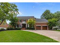 Beautiful brick home with a manicured lawn, mature trees, and a two-car garage at 6916 Cameron Glen Dr, Charlotte, NC 28210