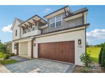 Modern two-story home with a stylish white and gray exterior and a brown wood garage door at 716 Flare Dr, Tega Cay, SC 29708