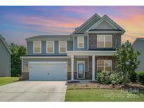 Charming two-story home featuring a two-car garage, beautiful landscaping, and a mix of brick and siding at 9285 Swimming Dr, Harrisburg, NC 28075