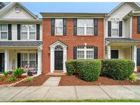 Charming brick-front townhome featuring manicured landscaping and black shutters at 10867 Garden Oaks Ln, Charlotte, NC 28273