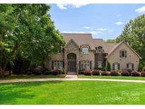 Elegant stone-and-stucco home with manicured lawn, mature trees, and lush landscaping at 1108 Shinnecock Ln, Waxhaw, NC 28173