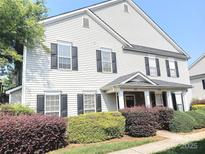 Two-story home featuring black shutters, light gray siding, and manicured landscaping with green and purple bushes at 1911 Flushing Ct, Charlotte, NC 28215