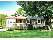 Charming single-story home featuring a stone porch, well-manicured lawn, and mature trees at 332 Daybrook Dr, Landis, NC 28088