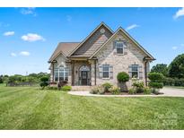 Charming brick home featuring a well-manicured lawn and inviting front porch, showcasing classic curb appeal at 3340 Emerald Pointe Ct, Monroe, NC 28110