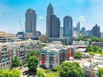 Condominium 401 N Church Street #201, with a downtown skyline in the background, brick exterior, and lush green trees at 401 N Church St # 201, Charlotte, NC 28202