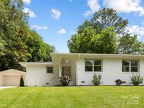 Charming single-story home with a white painted brick exterior, lush lawn, and a detached garage at 4929 Prentice Pl, Charlotte, NC 28210