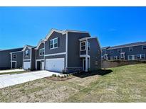 Modern townhome exterior with gray siding, white trim, and an attached garage on a sunny day at 7028 Alva Ter, Charlotte, NC 28216