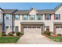 Inviting townhouse with a two-car garage, stone accents, manicured lawn, and colorful exterior at 709 Volta Nw Dr, Concord, NC 28027
